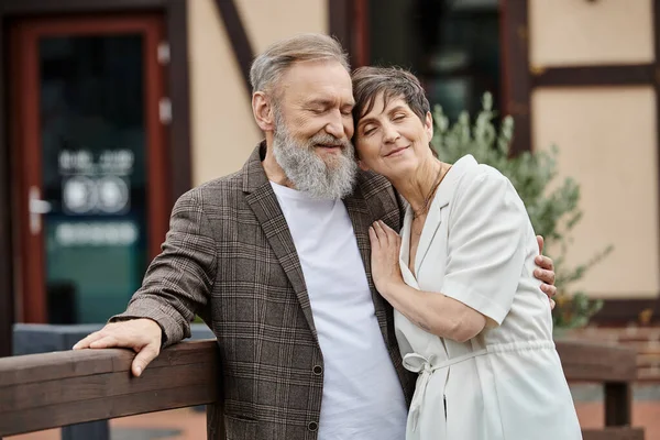 Счастливый бородатый мужчина и женщина обнимаются, пожилая пара с закрытыми глазами, романтика, любовь, пожилые люди на свидании — стоковое фото