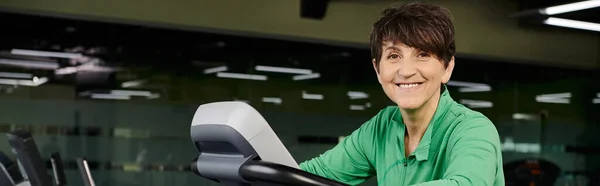 Active senior, happy elderly woman in sportswear exercising in gym, exercise machine, banner — Stock Photo