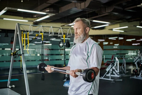 Atlético anciano con barba ejercitando con barbell en gimnasio, senior activo, atleta, fuerza — Stock Photo