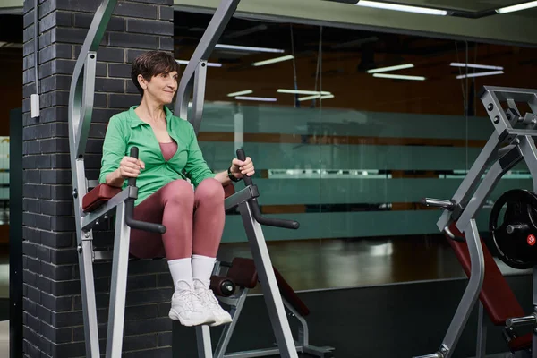 Joyeuse femme âgée souriant et travaillant dans la salle de gym, la motivation et le sport, dynamique et active — Photo de stock