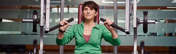 Femme âgée forte et motivée faisant de l'exercice en salle de gym, forme physique mature, énergie, senior actif, bannière — Photo de stock