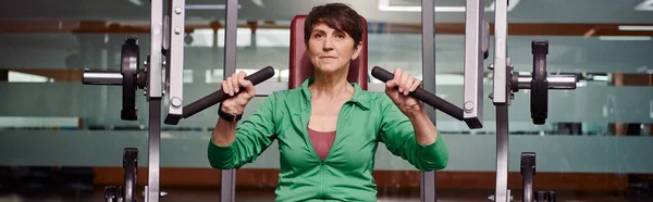 Strong and motivated elderly woman exercising in gym, mature fitness, energy, active senior, banner — Stock Photo