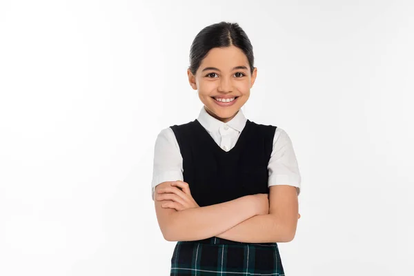 Happy schoolgirl in black vest standing with folded arms and looking at camera isolated on white — Stock Photo