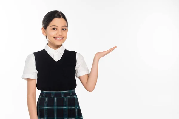Glückliches Schulmädchen zeigt etwas mit der Hand, zeigt und schaut in die Kamera, präsentiert, weiß — Stockfoto