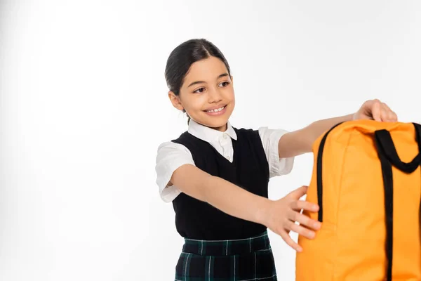 Positive schoolgirl taking backpack isolated on white, back to school concept, girl in uniform, joy — Stock Photo