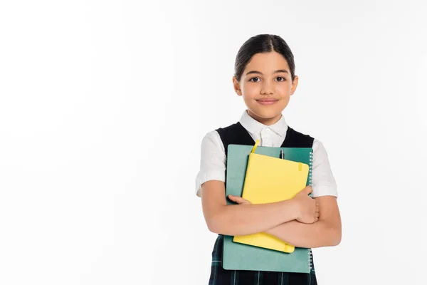 Happy schoolgirl standing with notebooks in hands and looking at camera isolated on white, student — Stock Photo