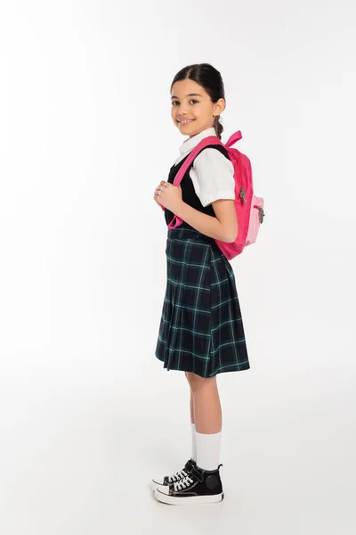 Ganzes, glückliches Schulmädchen in Uniform mit Rucksack auf weißem Grund, bereit für das neue Schuljahr — Stockfoto