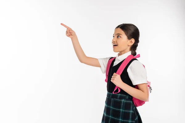 Amazed schoolgirl posing with finger away, looking at something, standing with backpack, student — Stock Photo