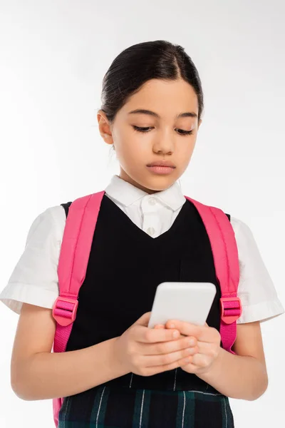 Âge numérique, écolière avec sac à dos en utilisant smartphone isolé sur blanc, étudiante en uniforme — Photo de stock