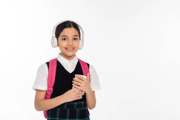 Digital age, cheerful schoolgirl in wireless headphones using smartphone isolated on white, student — Stock Photo
