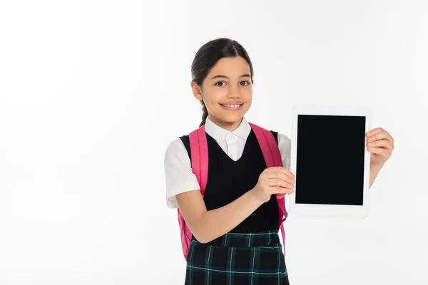 Счастливая школьница держит цифровой планшет с чистым экраном изолированы на белом, студент в форме — стоковое фото
