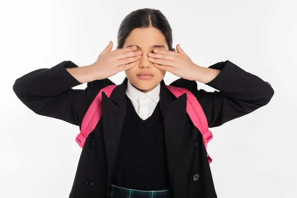 Schoolgirl in uniform covering eyes isolated on white, student in uniform, backpack, back to school — Stock Photo