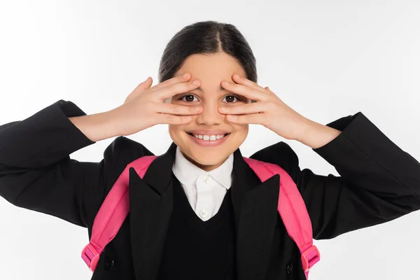 Happy schoolgirl in uniform covering eyes isolated on white, student life, looking at camera — Stock Photo
