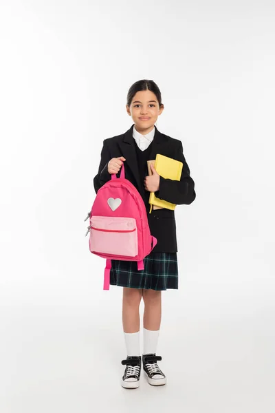 Радостная школьница стоя с ноутбуками и рюкзаком изолированы на белом, обратно в школу концепции — стоковое фото
