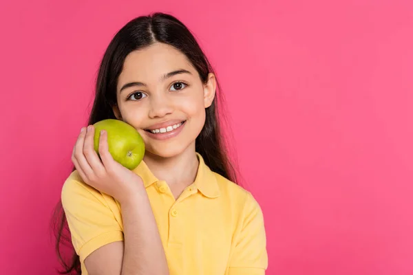 Portrait of happy brunette girl holding green and fresh apple isolated on pink, vibrant backdrop — Stock Photo