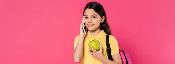 Happy schoolgirl standing with backpack, holding apple and talking on smartphone, phone call, banner — Stock Photo