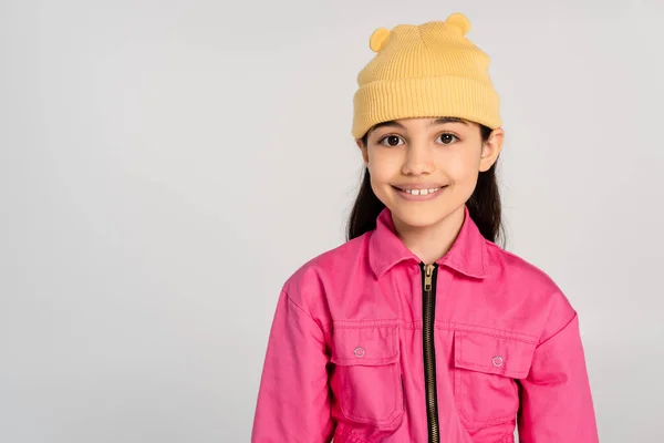 Fille heureuse en chapeau de bonnet jaune et tenue rose regardant la caméra sur fond gris, enfant élégant — Photo de stock