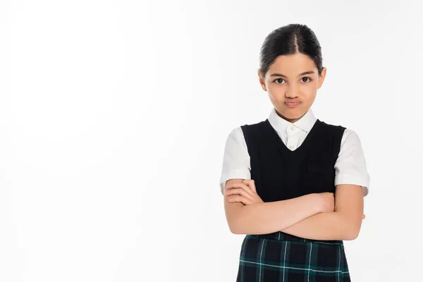 Portrait, offended schoolgirl in uniform looking at camera and standing with folded arms on white — Stock Photo