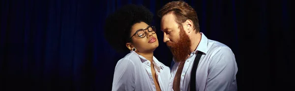 Séduisante femme afro-américaine aux lunettes flirtant près d'un homme d'affaires barbu au bureau, bannière — Photo de stock