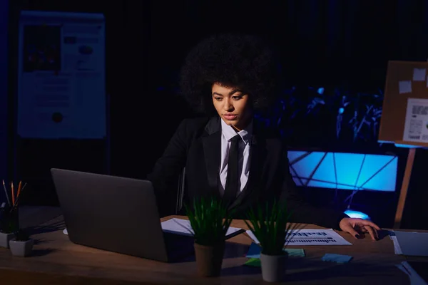 Mulher de negócios afro-americana em desgaste formal trabalhando no laptop no escritório escuro, turno da noite — Fotografia de Stock