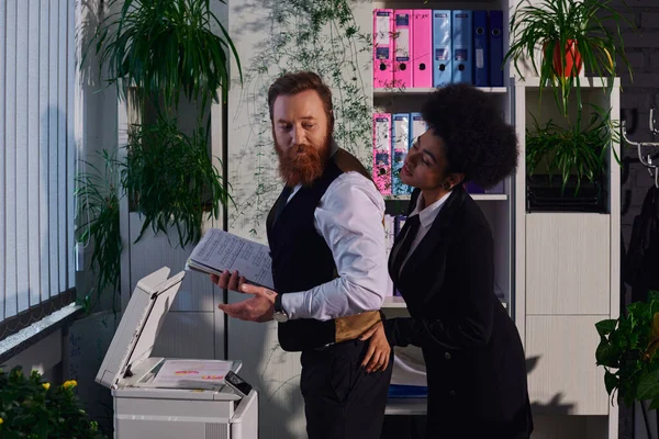 Young african american woman seducing bearded businessman standing with documents near copier — Stock Photo