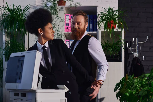 Бородатый бизнесмен соблазняет возмущенную африканскую американку возле ксерокса в офисе, домогательства — стоковое фото