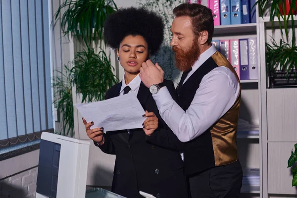 Homme d'affaires barbu touchant le visage de la jeune secrétaire avec un document près copieur dans le bureau, flirt — Photo de stock