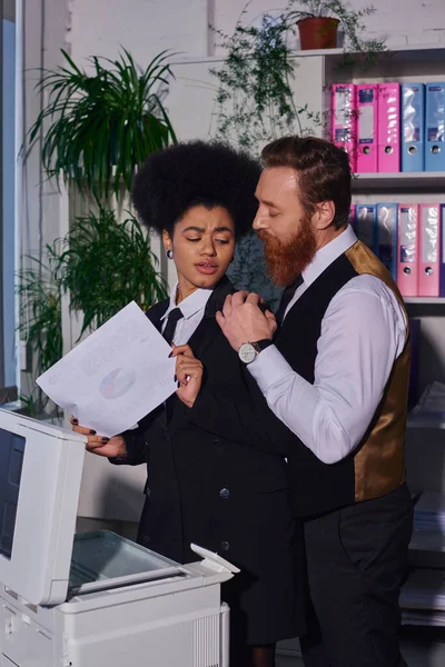 Незадоволена афроамериканська жінка відчуває дискомфорт біля бородатого бізнесмена, спокушаючи її в офісі — стокове фото