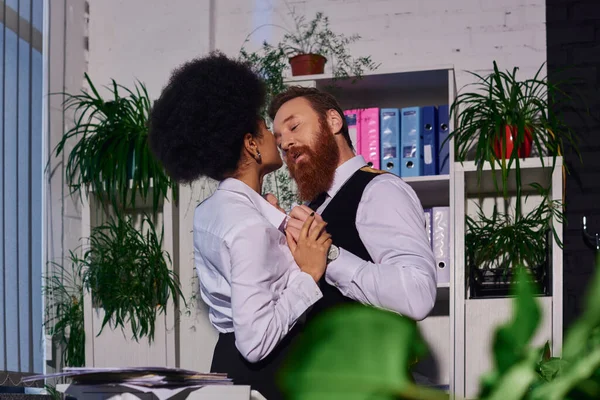 Pareja interracial, hombre de negocios barbudo y secretario afroamericano abrazándose en el cargo, pasión - foto de stock