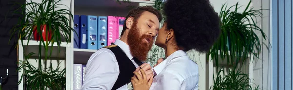 Homme barbu passionné près de jeune femme afro-américaine dans le bureau de nuit, amour au travail, bannière — Photo de stock