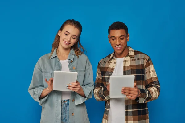 Glücklicher Mann und Frau mit digitalen Tablets auf blauem Hintergrund, sozialen Medien und Netzwerken — Stockfoto