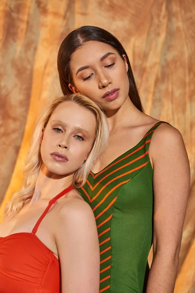 Portrait, multiethnic models in swimwear posing on beige backdrop with drapery, diversity and style — Stock Photo