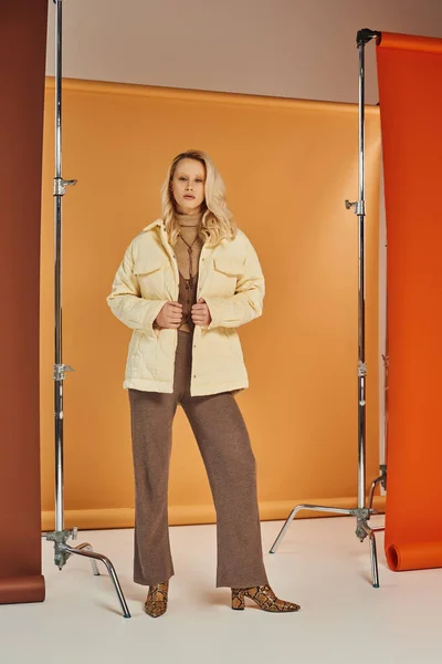 Modelo rubia en ropa de abrigo elegante y botas mirando a la cámara, posando en el estudio, la moda de otoño - foto de stock