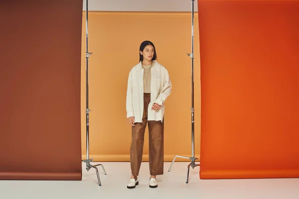 Bonita mujer asiática posando en traje de otoño, pantalones de cuero y ropa de abrigo, fondo multicolor — Stock Photo