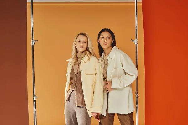 Autumn fashion, pretty multicultural models in warm season attire posing on colorful pastel backdrop — Stock Photo