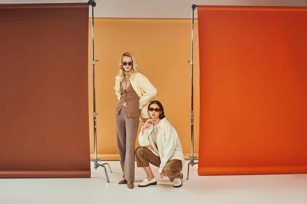 Models in Sonnenbrille und Herbstkleidung posieren vor buntem Hintergrund, Herbstfarben — Stockfoto