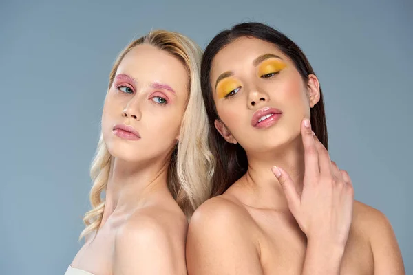 Vielfältiges Schönheitskonzept, multiethnische Frauen mit kühnem Augen-Make-up posieren auf blauem Hintergrund, feminin — Stockfoto