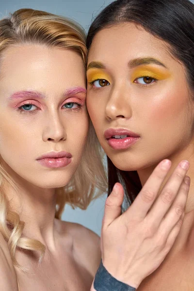 Diversifiziertes Schönheitskonzept, interrassische Models mit kühnem Augen-Make-up vor blauem Hintergrund — Stockfoto