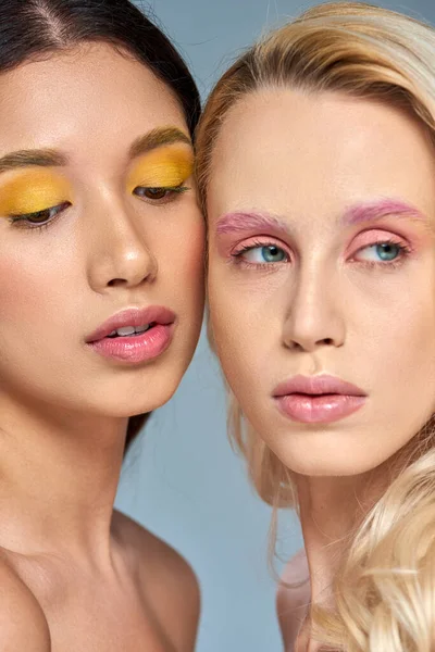 Modelos multiculturais com maquiagem olho ousado posando juntos no fundo azul, olhos expressivos — Fotografia de Stock