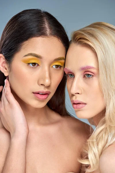 Multikulti-Models mit kühnem Augen-Make-up posieren gemeinsam vor blauem Hintergrund, Beauty-Trend-Konzept — Stockfoto