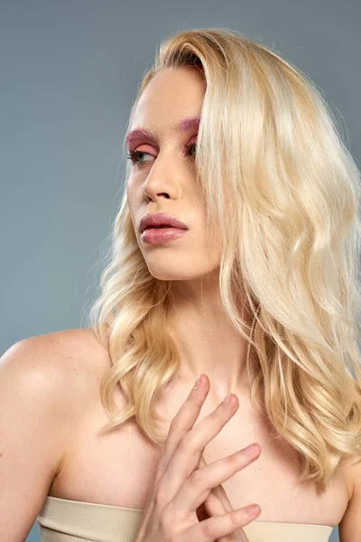Sensual woman with pink eye makeup and blonde hair posing on grey backdrop, feminine beauty — Stock Photo