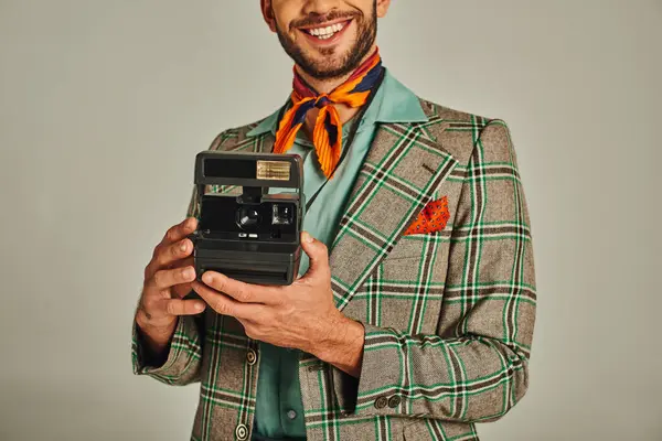 Corte vista de homem sorridente em jaqueta xadrez segurando câmera vintage em cinza, estilo de vida retro-inspirado — Fotografia de Stock