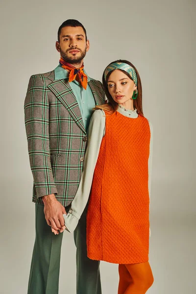 Casal old-fashioned em elegante traje vintage de mãos dadas, enquanto em pé no fundo cinza — Fotografia de Stock