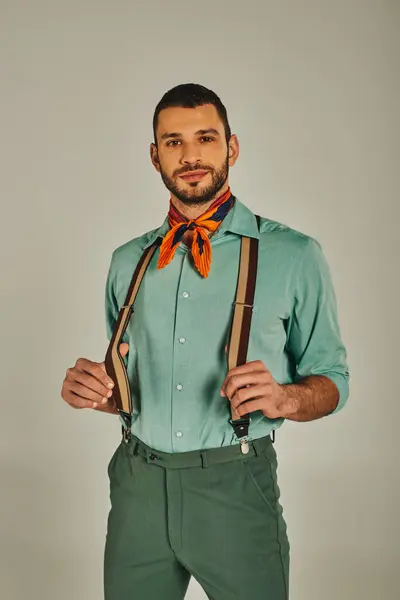Uomo positivo in bretelle e collo colorato guardando la fotocamera su grigio, stile retrò di ispirazione — Foto stock