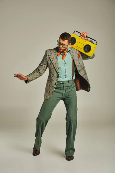 Piena lunghezza di giovane e alla moda vecchio stile uomo con boombox giallo danza su grigio, stile retrò — Foto stock