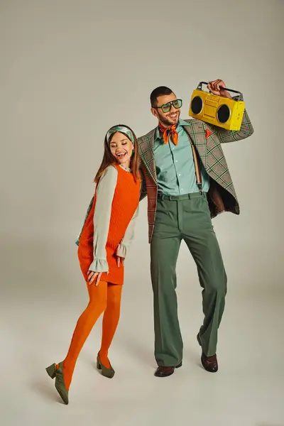 Happy old-fashioned couple with yellow boombox dancing on grey, entertainment and retro lifestyle — Stock Photo