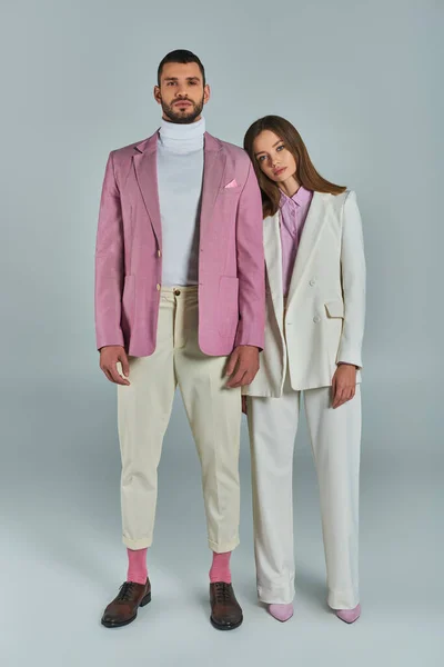 Pleine longueur de jeune couple en tenue formelle élégante regardant la caméra sur gris, mode minimaliste — Photo de stock