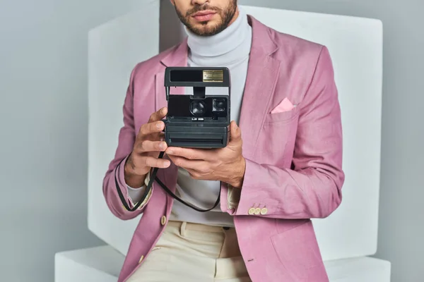 Vista cortada do homem moderno em blazer lilás tirar foto na câmera vintage perto de cubos brancos em cinza — Fotografia de Stock