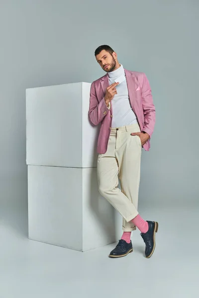 Elegante uomo in blazer lilla in piedi con mano in tasca e biglietto da visita vuoto vicino cubi su grigio — Foto stock