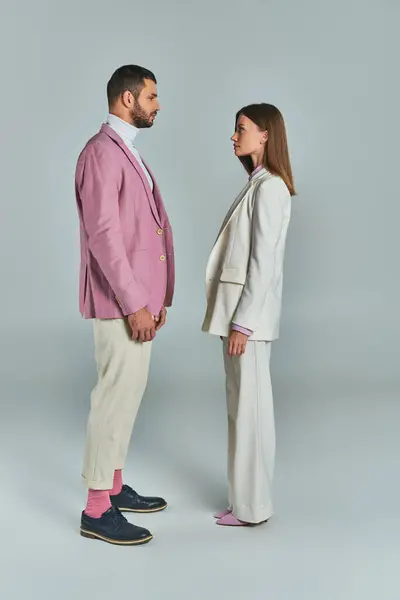 Full length of young couple in stylish suits looking at each other on grey, modern business fashion — Stock Photo